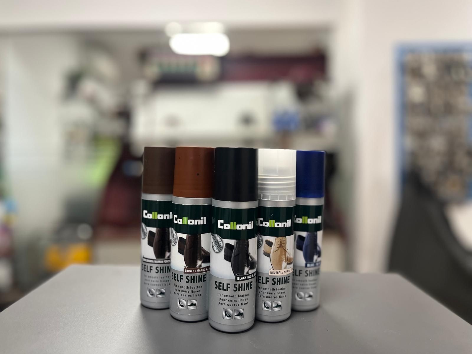 Five cans of Collonil Self Shine leather care products in various colors on a table.